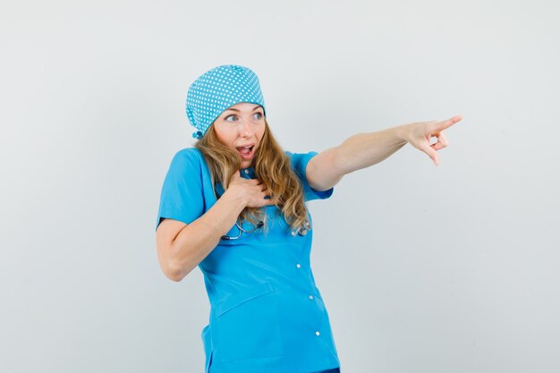 Medico femminile che indica via in uniforme blu e che sembra stupito.