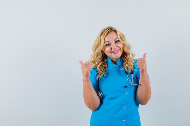 Medico femminile che mostra il pollice in su in uniforme blu e che sembra contento. spazio per il testo
