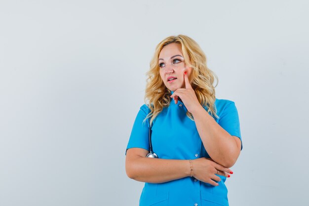 Medico femminile che osserva via in uniforme blu e che osserva concentrato. spazio per il testo