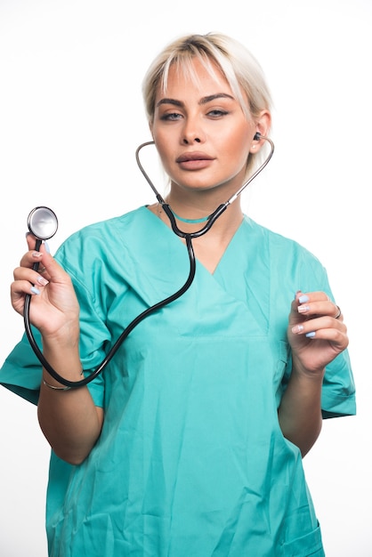 Medico femminile che per mezzo dello stetoscopio sulla superficie bianca