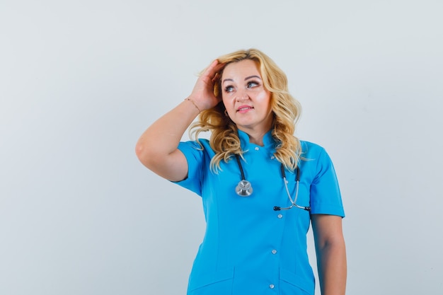 Medico femminile che regola i capelli mentre osserva da parte in uniforme blu