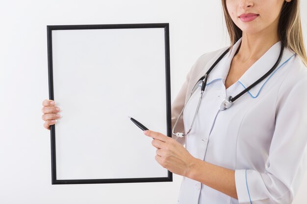 Medico femminile che tiene una carta in bianco