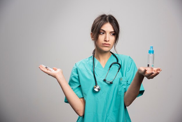 Medico femminile con lo stetoscopio che tiene la bottiglia dello spruzzo