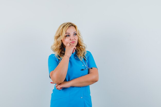 Medico femminile concentrandosi da parte in uniforme blu e guardando attento.