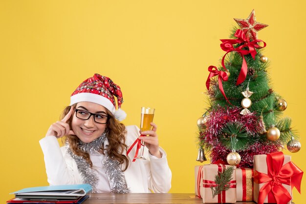 Medico femminile di vista frontale che celebra il natale con un bicchiere di champagne