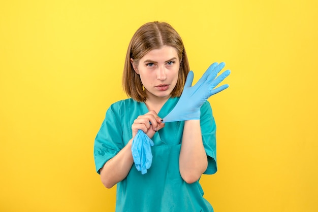 Medico femminile di vista frontale che indossa guanti blu su spazio giallo