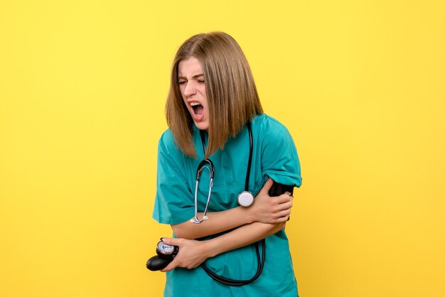 Medico femminile di vista frontale che per mezzo del tonometro su spazio giallo