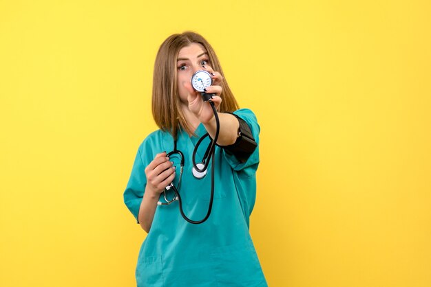 Medico femminile di vista frontale che per mezzo del tonometro su spazio giallo