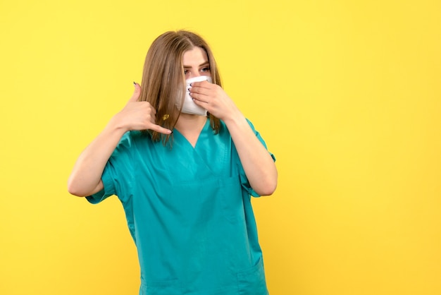 Medico femminile di vista frontale che porta maschera sullo spazio giallo
