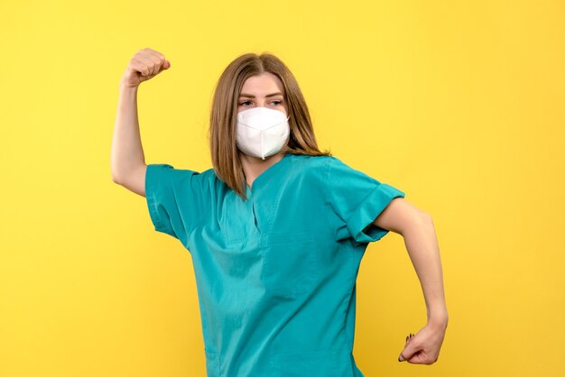 Medico femminile di vista frontale che posa con la maschera sullo spazio giallo