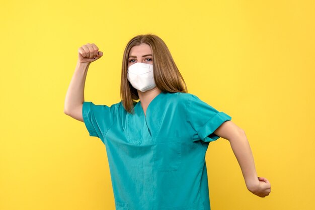 Medico femminile di vista frontale che posa con la maschera sullo spazio giallo