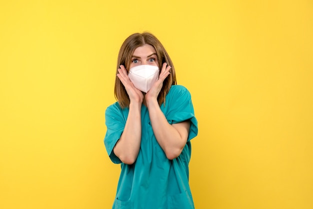 Medico femminile di vista frontale che posa con la maschera sullo spazio giallo