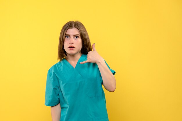 Medico femminile di vista frontale che posa sullo spazio giallo chiaro