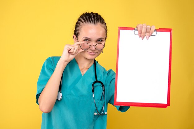 Medico femminile di vista frontale che tiene appunti medici vuoti, salute dell'erba medica covid-19 di emozione dell'infermiera di colore