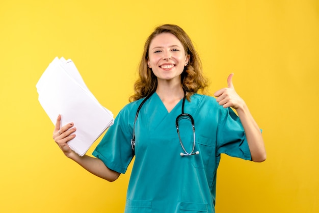 Medico femminile di vista frontale che tiene archivi su spazio giallo