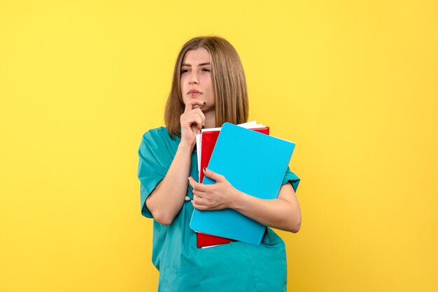 Medico femminile di vista frontale che tiene i documenti sullo spazio giallo