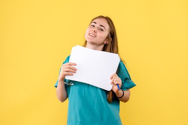 Medico femminile di vista frontale con documentazione su un ospedale di salute dell'infermiera del fondo giallo