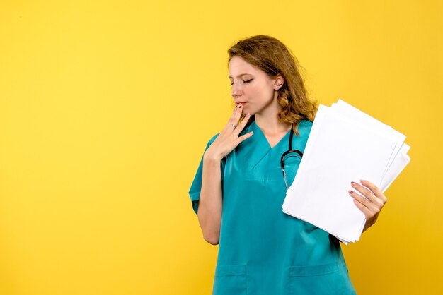 Medico femminile di vista frontale con gli archivi che pensano sullo spazio giallo