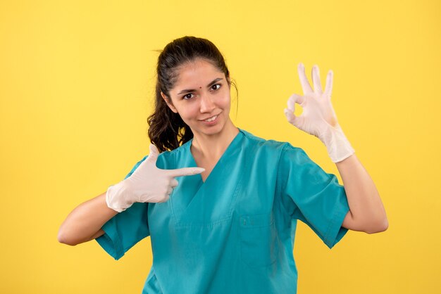 Medico femminile di vista frontale con i guanti di lattice che fanno il segno okey