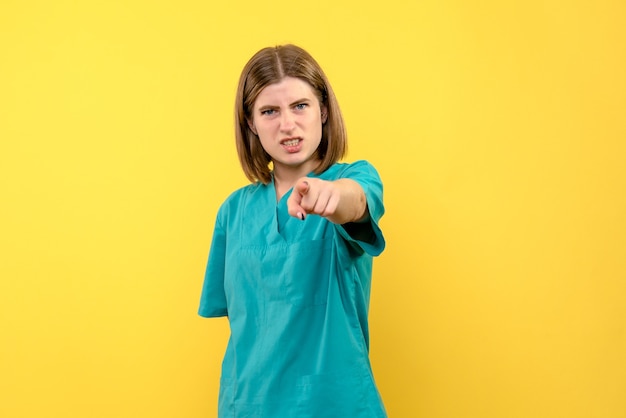 Medico femminile di vista frontale con l'espressione arrabbiata sullo spazio giallo