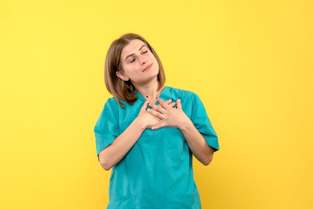 Medico femminile di vista frontale con la faccia felice sullo spazio giallo