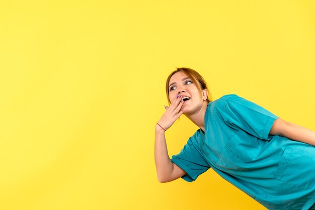 Medico femminile di vista frontale eccitato sullo spazio giallo