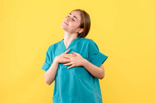 Medico femminile di vista frontale felice sulla salute dell'ospedale di emozione medica del fondo giallo