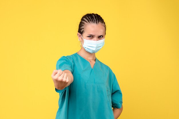 Medico femminile di vista frontale in camicia e maschera mediche, colore pandemico covid-19 dell'ospedale dell'infermiera di salute del virus