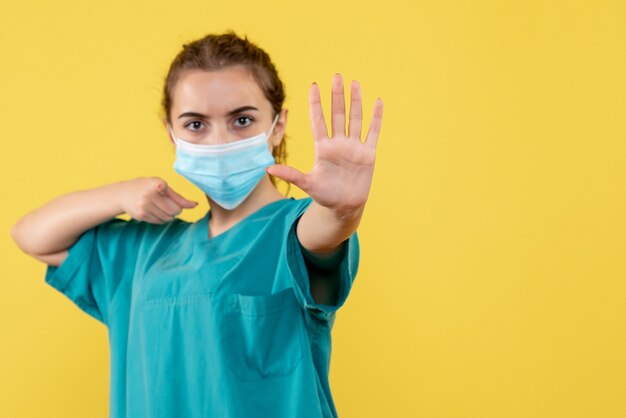 Medico femminile di vista frontale in camicia e maschera mediche, pandemia covid-19 uniforme di colore di salute