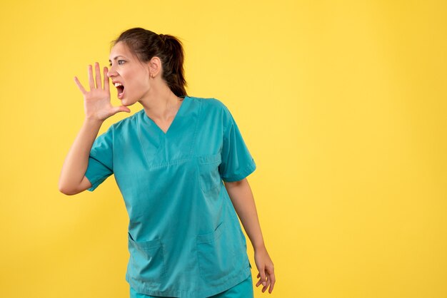 Medico femminile di vista frontale in camicia medica che chiama su priorità bassa gialla