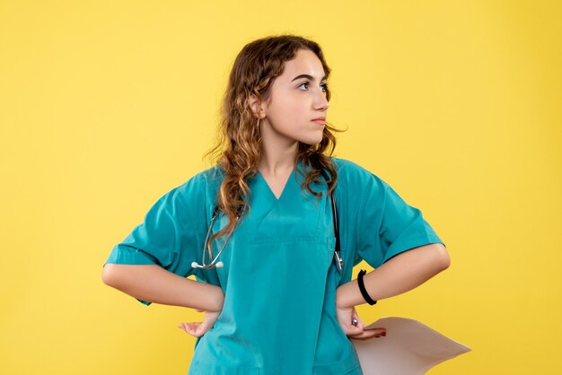 Medico femminile di vista frontale in camicia medica che tiene analisi della carta, emozione covid-19 uniforme del virus della salute pandemica