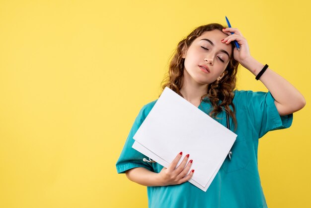 Medico femminile di vista frontale in camicia medica che tiene analisi della carta, emozione pandemica di salute del virus covid-19