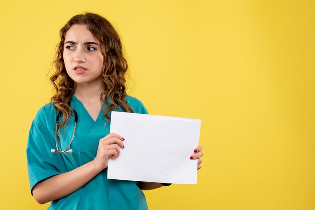Medico femminile di vista frontale in camicia medica che tiene analisi della carta, emozione uniforme covid-19 del virus di salute