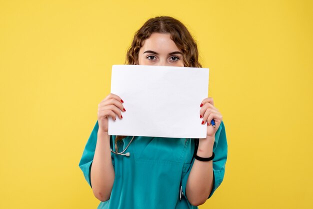 Medico femminile di vista frontale in camicia medica che tiene analisi della carta, emozione uniforme covid-19 di salute pandemica