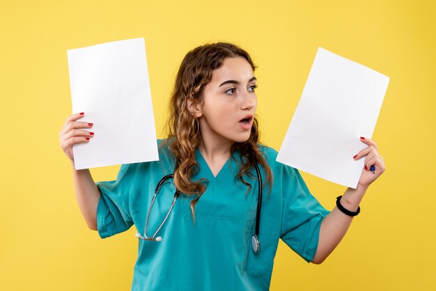 Medico femminile di vista frontale in camicia medica che tiene analisi della carta, emozioni pandemiche di salute covid-19 uniformi del virus