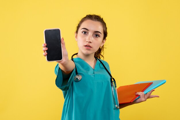 Medico femminile di vista frontale in camicia medica con note e telefono, virus covid-19 pandemico uniforme di emozione di salute