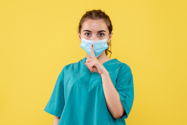 Medico femminile di vista frontale in camicia medica e maschera, colore uniforme del virus covid-19 pandemico di salute