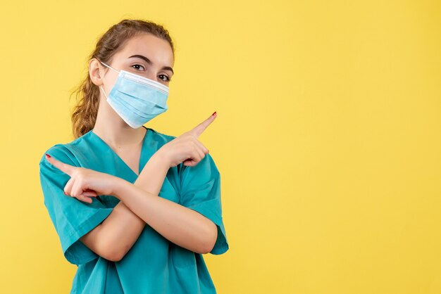 Medico femminile di vista frontale in camicia medica e maschera sterile, salute pandemica covid virus uniforme di malattia coronavirus
