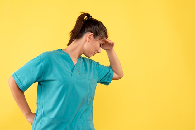 Medico femminile di vista frontale in camicia medica ha sottolineato su priorità bassa gialla