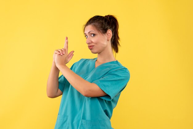 Medico femminile di vista frontale in camicia medica su una priorità bassa gialla