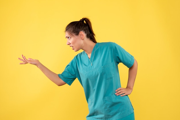 Medico femminile di vista frontale in camicia medica su una priorità bassa gialla