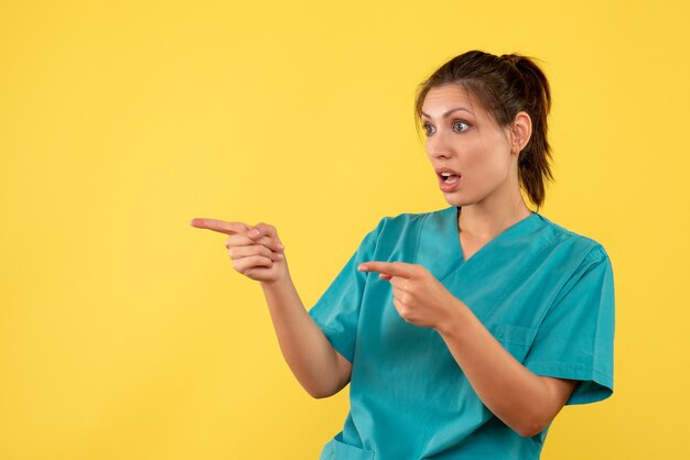 Medico femminile di vista frontale in camicia medica su una priorità bassa gialla