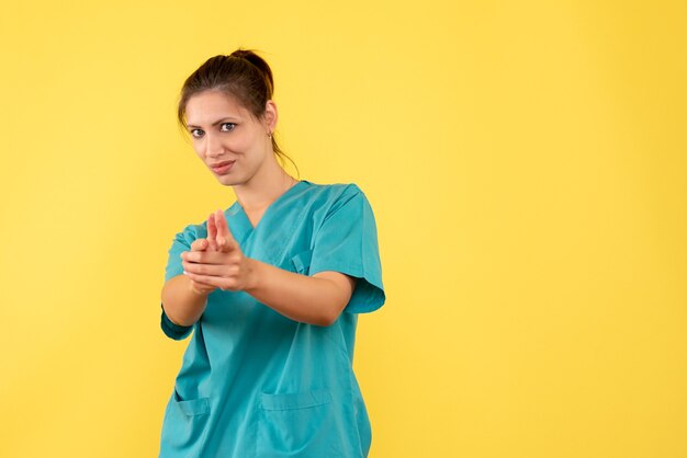 Medico femminile di vista frontale in camicia medica su una priorità bassa gialla