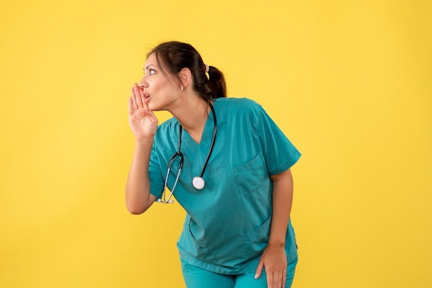 Medico femminile di vista frontale in camicia medica su una priorità bassa gialla