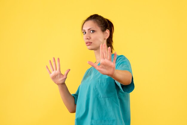 Medico femminile di vista frontale in camicia medica su una priorità bassa gialla