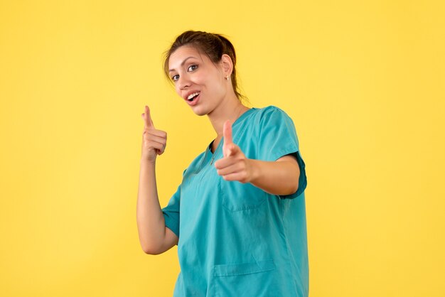 Medico femminile di vista frontale in camicia medica su una priorità bassa gialla