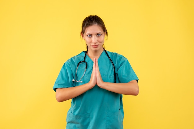 Medico femminile di vista frontale in camicia medica su una priorità bassa gialla