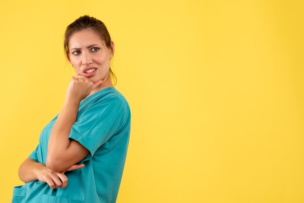 Medico femminile di vista frontale in camicia medica su una priorità bassa gialla