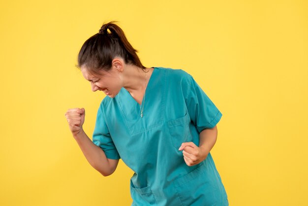 Medico femminile di vista frontale in camicia medica su una priorità bassa gialla