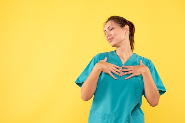 Medico femminile di vista frontale in camicia medica sul colore giallo di salute del virus dell'infermiera dell'ospedale di covid dello scrittorio giallo